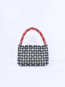 Detailed view of handmade beaded square bag with red handles and black floral pattern