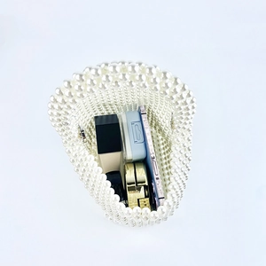 Detail view of handmade pearl beaded handbag showing interior space with phone and makeup