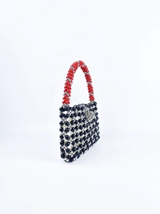 Detail of handmade beaded handbag with black silver weave and red contrast handle