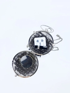 Detail view of silver spherical evening bag with metal mesh texture and chain strap
