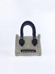 Detailed shot of handmade silver beaded handbag featuring a black pearl smiley face