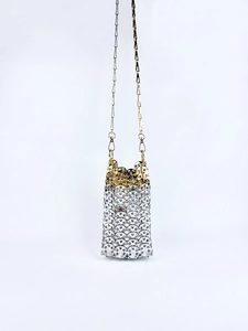 Macro detail of the cylinder handbag featuring silver and gold metal rings woven texture