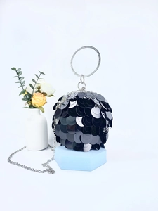 Detailed view of black sequin ball evening bag with silver ring handle on display stand