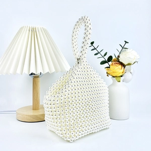 Detailed close-up of handmade white pearl beaded handbag with woven texture and handle