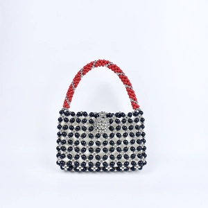 Close-up of handmade beaded bag with red handles and floral silver clasp detail