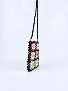 Close-up of handmade beaded crossbody bag with colorful floral patterns and black strap