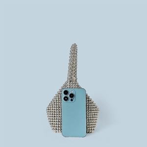 Detail of silver beaded handbag with phone for size comparison on a blue background