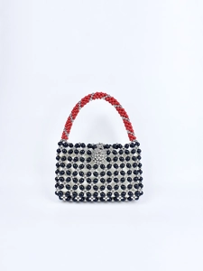 Detail of handmade beaded tote featuring black floral hollow patterns and red spiral handles