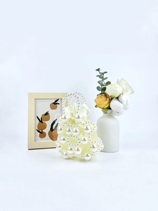 Elegant beaded pearl handbag with cream satin lining and drawstring closure on white background