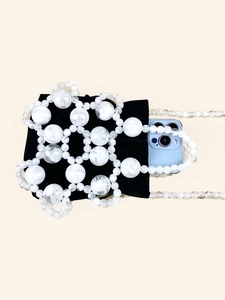 Chic black velvet bucket bag with marble beads and long beaded strap on beige background