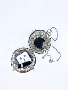 Detailed interior view of silver sphere evening bag with mirror, sequins and chain strap