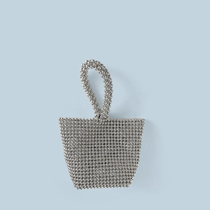 Detailed macro view of silver metallic beads and circular handle on the woven mini bag