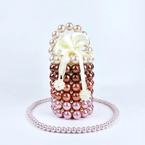Detail of handmade beaded bucket bag with gradient pearls and a large yellow satin bow