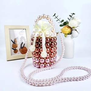 Detail of gradient pink handmade pearl bucket bag with ribbon bow and gold beads