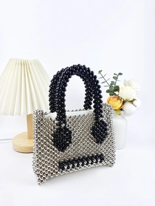 Handcrafted silver beaded handbag with black smiley face design on a minimalist background