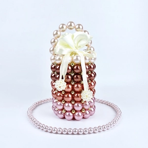 Detail of handmade beaded bucket bag with tri-color gradient pearls and silk bow