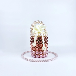 Detailed view of handmade beaded bucket bag with gradient pearls and a satin bow charm