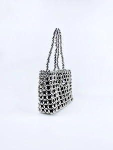 Detailed view of silver metallic bead weave and hollow grid texture on top handle bag