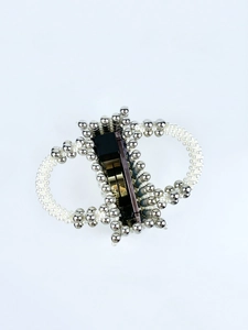 Macro shot of stylish CD logo hair claw clip with faux white pearls and silver beads