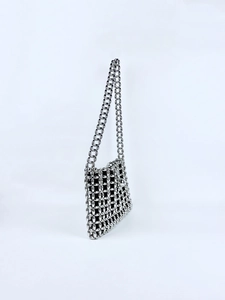Detail of silver metallic beaded shoulder bag showing hollow grid and black lining texture