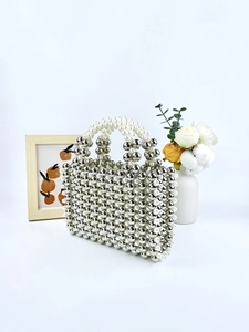 Handmade beaded mini tote bag with metallic silver and white pearl beads in a still life setting