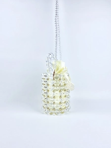 Detail of handcrafted barrel bag with transparent beads and golden metal accents