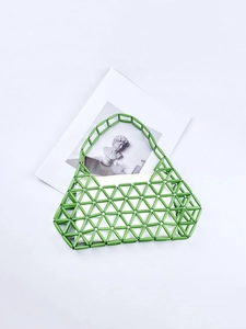 Green beaded woven handbag with white inner pouch on artistic background book