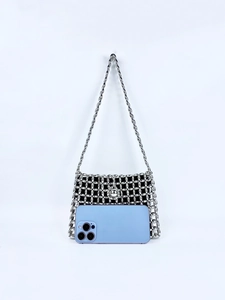 Detail of silver beaded handbag showing hollow metal mesh design with black fabric lining
