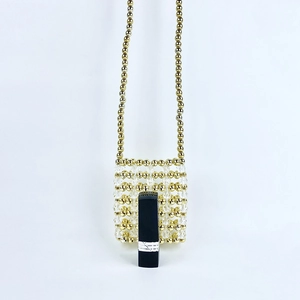 Detailed close-up of handmade beaded mini bag with gold and clear beads next to a lipstick