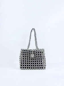 Detailed view of silver beaded woven handbag with contrasting black inner lining
