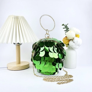 Macro detail of sphere evening bag featuring shimmering green sequins and golden ring handle