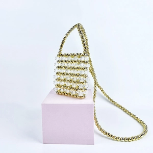 Exquisite handmade beaded mini handbag with transparent and gold beads on a pink pedestal