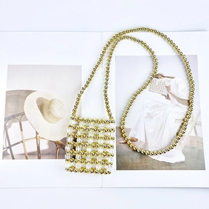 Detail of handcrafted gold and clear beaded mini crossbody bag on a fashion magazine
