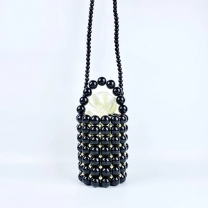 Detail of handmade black beaded bucket bag with golden accents and satin drawstring lining
