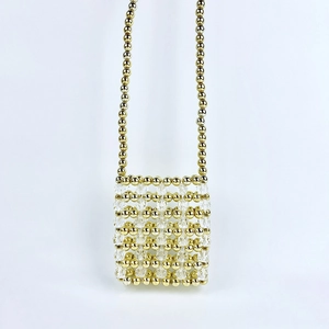 Detail of handmade mini beaded bag featuring gold beads and transparent crystal textures