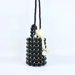 Detail of handmade black beaded bucket bag featuring a white satin drawstring pouch