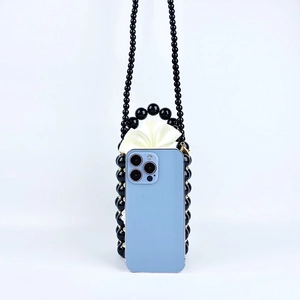 Detail of hand-woven black beaded bucket bag with pearl handle and smartphone size reference