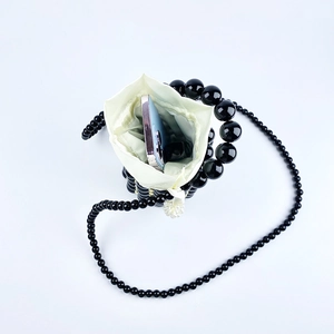 Detailed view of the black beaded cylinder bag showing internal space for a smartphone