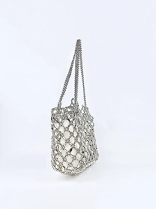 Detail of silver metallic beaded tote bag showing hollow-out design and white inner lining