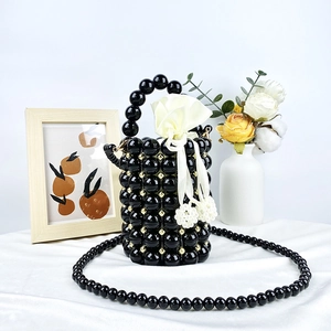 Detail of beaded bucket bag featuring a white satin drawstring pouch and floral decor