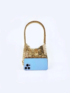 Macro detail of a gold sequin handbag with a blue smartphone showing size comparison
