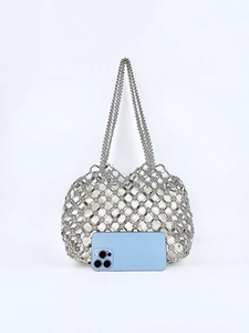 Detail of silver beaded hollow handbag with white fabric inner bag and woven metal mesh