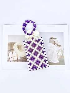 Handmade beaded handbag with purple crystals, pearls and a silk bow on white background