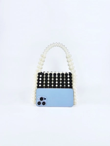 Mini sac perlé fait main avec motifs noirs et blancs et smartphone pour échelle de taille