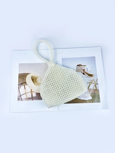 Elegant white triangular faux pearl beaded handbag with circular top handle on a magazine