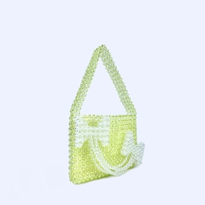 Detail of light green handmade beaded handbag with decorative bows and 3D textures