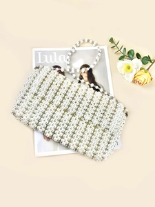 Exquisite handmade white pearl woven handbag on a fashion magazine with flowers