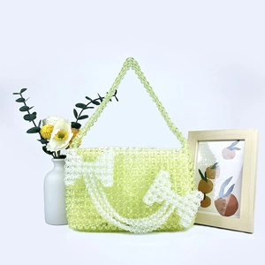 Detail of green handmade acrylic beaded bag with white bow pattern and top handle
