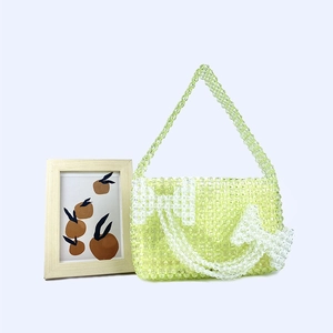 Detailed close-up of handmade acrylic beaded shoulder bag with white bow accents