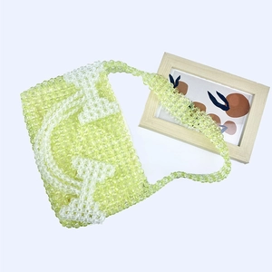 Macro detail of hand-woven light green beaded handbag with white geometric pattern